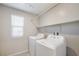 A well-lit laundry room with modern washer and dryer, and shelving at 7629 Rosebark Cliffs St, North Las Vegas, NV 89084