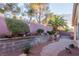 Landscaped backyard with a brick retaining wall, mature trees, and brick-paved pathway at 8433 Sea Glen Dr, Las Vegas, NV 89128