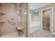 Bathroom featuring glass-enclosed shower, and a soaking tub with a light brown and white color palette at 870 Santa Maria Way, Mesquite, NV 89027
