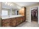 Bathroom with double sink vanity, a large mirror, wooden cabinetry, a shower, and a walk-in closet at 870 Santa Maria Way, Mesquite, NV 89027