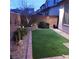 A cozy backyard features synthetic grass, decorative landscaping and stone details at 10976 Bluebell Basin Rd, Las Vegas, NV 89179