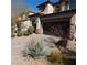 Two-story home with desert landscaping, a dark garage door, and a paved driveway at 10976 Bluebell Basin Rd, Las Vegas, NV 89179