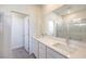 Bathroom featuring a double sink vanity with quartz countertops, a large mirror, and a glass-enclosed shower at 11576 Ashy Storm Ave, Las Vegas, NV 89138