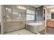 This bathroom features a glass enclosed shower and tub with tan tiling and lots of natural light at 12118 La Carta Ct, Las Vegas, NV 89138