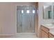 Bright bathroom featuring a glass enclosed shower, light cabinets and neutral tile floors at 1534 Waterford Falls Ave, Las Vegas, NV 89123