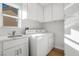 Bright laundry room featuring a modern washer and dryer, ample cabinetry and a sink with stone countertops at 2612 Springridge Dr, Las Vegas, NV 89134