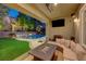 Covered patio with an outdoor seating area and a TV, overlooking the pool and the landscaped backyard at 2796 Rosenhearty Dr, Henderson, NV 89044