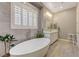 Bright bathroom features soaking tub, shutters, double vanity and wood-look tile floor at 2796 Rosenhearty Dr, Henderson, NV 89044