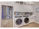 Well-equipped laundry room with a wine fridge, washer/dryer, shaker cabinets, and a charming farmhouse sink at 2796 Rosenhearty Dr, Henderson, NV 89044