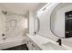 Beautifully renovated bathroom featuring a dual sink vanity, sleek black fixtures and a marble tiled shower and tub at 2921 Moonlight Bay Ln, Las Vegas, NV 89128