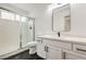 Modern bathroom with white cabinets, black hardware, a glass-enclosed shower, and sleek tile flooring at 2921 Moonlight Bay Ln, Las Vegas, NV 89128