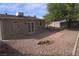 Large gravel backyard featuring a brick patio, mature tree, and storage shed at 4816 Greencreek Dr, Las Vegas, NV 89110