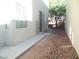 Exterior view of the side of the house with concrete walkway, rock landscaping and neutral walls at 5490 Floating Flower Ave, Las Vegas, NV 89139