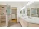 Bright bathroom featuring double sinks with a stone countertop, a glass shower, and walk-in closet at 5517 Whiteleaf Ct, Las Vegas, NV 89149