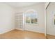 Sunlit bedroom with hardwood floors, built-in shelving, plantation shutters, and mirrored closet doors at 5517 Whiteleaf Ct, Las Vegas, NV 89149