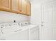 Bright laundry room with a white washer and dryer, light wood cabinets and white walls, complete with a white door at 5517 Whiteleaf Ct, Las Vegas, NV 89149