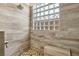 Modern shower design with stone tiles, a glass block window, and a built-in bench at 5517 Whiteleaf Ct, Las Vegas, NV 89149