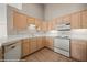 Well-lit kitchen featuring light wood cabinets, white appliances, and tile countertops at 701 Aztec Cir, Mesquite, NV 89027