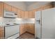 Corner view of kitchen with wood cabinets, white appliances, and tile flooring at 701 Aztec Cir, Mesquite, NV 89027