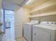 Bright laundry room featuring washer, dryer, and overhead shelves for efficient storage solutions at 7117 Shadow Crest Dr, Las Vegas, NV 89119