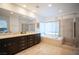 Bright bathroom featuring a soaking tub with beige tile surround, double sink vanity, and a glass-enclosed shower at 204 N Ring Dove Dr, Las Vegas, NV 89144