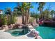 Inviting backyard pool with rock waterfall feature, spa, lush landscaping, and mature palm trees at 204 N Ring Dove Dr, Las Vegas, NV 89144