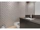 Modern powder room featuring a unique textured wall, floating vanity with dark countertop, and sleek fixtures at 43 Grey Feather Dr, Las Vegas, NV 89135