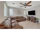 Cozy living room with a large brown leather sectional, wooden console, and a modern ceiling fan at 7856 Pyramid Peak St, Las Vegas, NV 89166