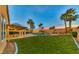 Lush backyard with a well-maintained lawn, a sparkling pool, and a covered patio at 283 Auster Park Ave, Las Vegas, NV 89148
