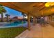 Covered patio with an outdoor seating area overlooking a pristine pool and landscaped backyard at 283 Auster Park Ave, Las Vegas, NV 89148