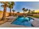 Inviting pool and spa with a slide, surrounded by a beautifully landscaped backyard with palm trees at 283 Auster Park Ave, Las Vegas, NV 89148