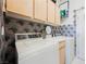 Cozy laundry area featuring light wood cabinets, patterned wallpaper, and a functional washer and dryer at 299 Francisco St, Henderson, NV 89014