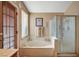 Bathroom featuring a soaking tub, glass enclosed shower, wood-look tile and a wood slat door to exterior at 3181 Shadow Bluff Ave, Las Vegas, NV 89120