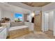 Bright bathroom featuring a soaking tub, travertine tile, and views of the city skyline at 360 E Desert Inn Rd # 604, Las Vegas, NV 89109