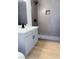 Modern bathroom with a gray tiled shower, gray vanity, and wood-look tile floors at 4818 E Monroe Ave, Las Vegas, NV 89110