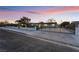 Street-level view of the property showcasing a gated entry and long driveway under a colorful twilight sky at 616 Lacy Ln, Las Vegas, NV 89107