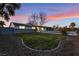 Charming front yard featuring green lawn and mature trees, set against a backdrop of a vibrant twilight sky at 616 Lacy Ln, Las Vegas, NV 89107