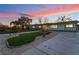 Well-manicured front yard featuring lush grass and mature trees, framed by a colorful twilight sky at 616 Lacy Ln, Las Vegas, NV 89107