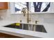 Close up view of a stainless steel kitchen sink and faucet with white countertops and natural light at 616 Lacy Ln, Las Vegas, NV 89107