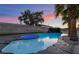 A beautiful pool with a waterfall feature, stone accents, and palm trees at 616 Lacy Ln, Las Vegas, NV 89107