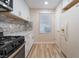 Efficient kitchen with stainless steel appliances, white cabinets, stone backsplash, and wood-look floors, ready for meal preparation at 629 Alecandro Daniel Ave, North Las Vegas, NV 89031