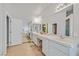 Bright bathroom featuring dual sinks, white cabinetry, and a doorway leading to a bathtub and shower at 6710 Pyracantha Glen Ct, Las Vegas, NV 89131
