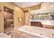 Bright bathroom featuring a soaking tub, glass enclosed shower, and dark wood vanity at 11342 Winter Cottage Pl, Las Vegas, NV 89135