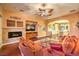 The cozy living room offers wood floors, a decorative ceiling fan, and a stone fireplace at 11342 Winter Cottage Pl, Las Vegas, NV 89135