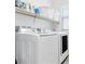 Clean laundry room with modern, white appliances, built-in shelving, and a bright window at 12125 Arrebol Ave, Las Vegas, NV 89138