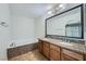 Bathroom featuring dual sinks with granite countertops, a large mirror, and a soaking tub at 1810 N Decatur Blvd # 201, Las Vegas, NV 89108