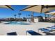 Community pool with lounge chairs, umbrellas, palm trees, and clear blue skies at 2734 Champagne Gold Ave, North Las Vegas, NV 89086