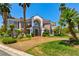 Elegant two-story home with a grand entrance, lush landscaping, mature palm trees, and a circular driveway at 3341 Camino Gardens Way, Las Vegas, NV 89146
