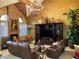 Living room featuring two brown leather sofas, vaulted ceilings and a brick fireplace at 3341 Camino Gardens Way, Las Vegas, NV 89146