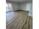 Open-concept living room features wood-look laminate flooring and sliding glass door access to balcony at 5241 River Glen Dr # 184, Las Vegas, NV 89103